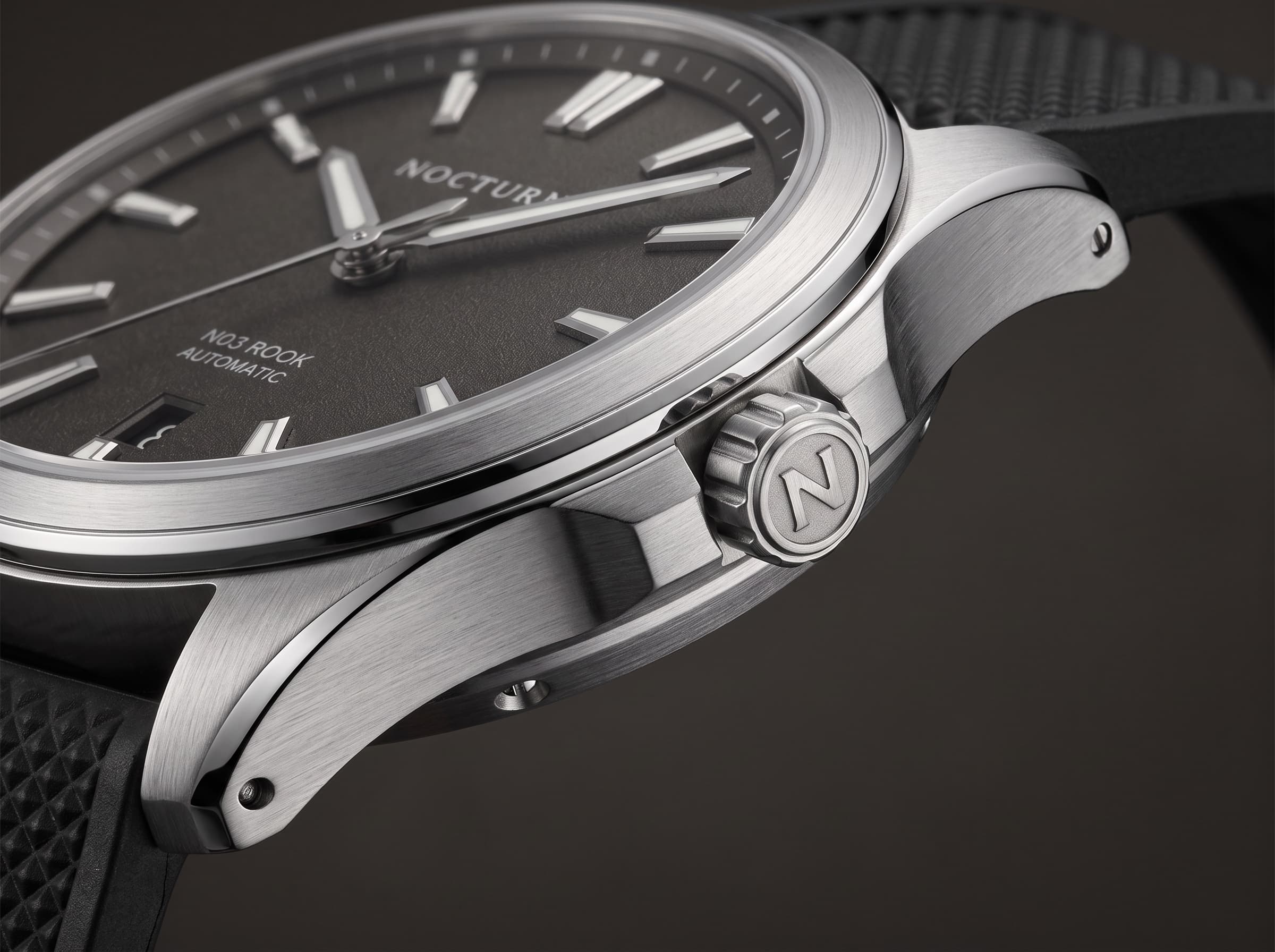 Close detail of the Rook brushed case, crown, graphite dial, and rubber strap